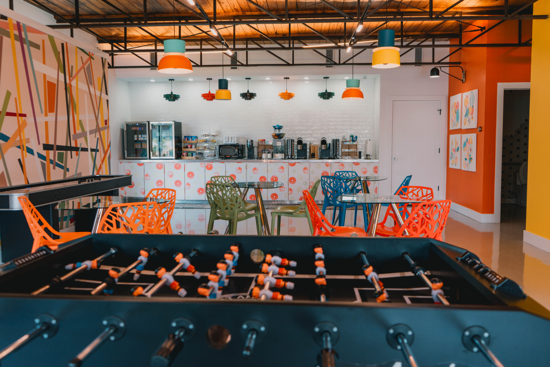 Game room with a foosball table, colorful chairs, and the coffee bar
