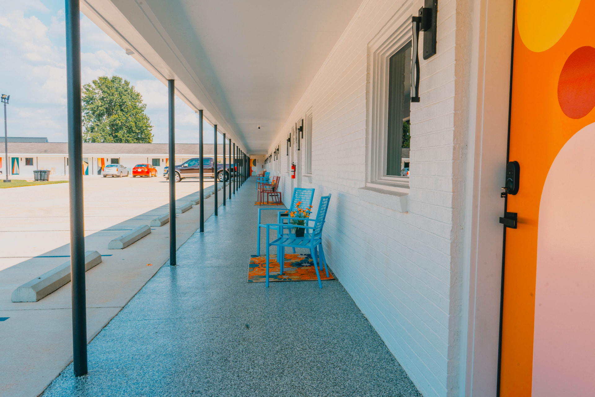 Covered walkway with bright blue chairs outside the guest rooms